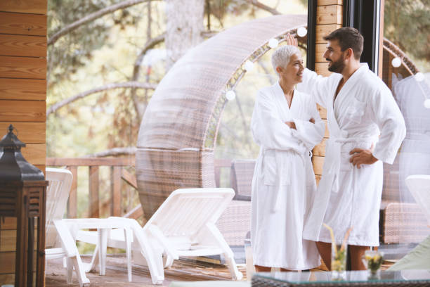 Vacation flirt Copy space shot of a mature woman talking to young man at the hotel resort. They are both wearing bathrobes after spa treatment. cougar woman stock pictures, royalty-free photos & images
