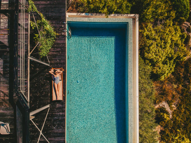 Vacation for one Aerial view of a young woman relaxing by the infinity pool vacation rental photos stock pictures, royalty-free photos & images