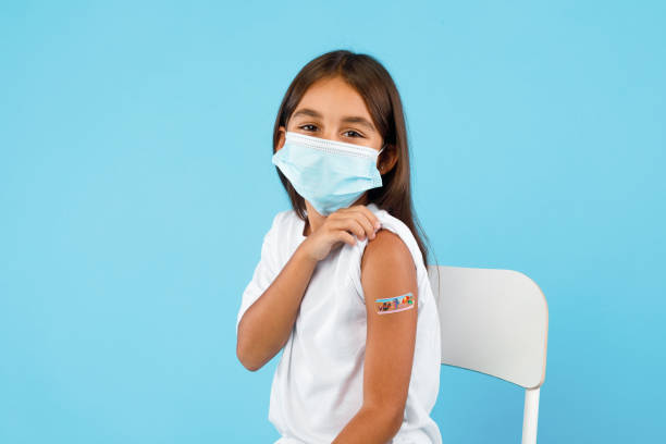 Vaccinated Arabic Little Girl Showing Arm After Vaccination, Blue Background stock photo