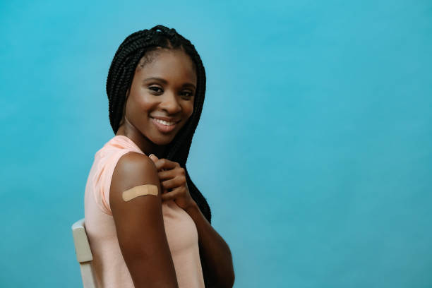 Vaccinated attractive young woman with plaster on hand right after getting covid-19 vaccine shot stock photo