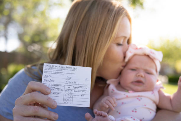 Vaccination Card A mother with a proof of Vaccination card and her new born baby girl. cdc vaccine card stock pictures, royalty-free photos & images