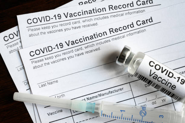 COVID-19 Vaccination Record Card on desk, top view of coronavirus immunization certificate COVID-19 Vaccination Record Card on desk, top view of coronavirus immunization certificate. Syringe and COVID vaccine bottle are on medical form required for travel. Corona virus and tourism concept. cdc vaccine card stock pictures, royalty-free photos & images