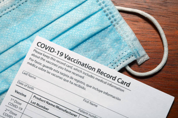COVID-19 Vaccination Record Card A blank COVID-19 vaccination record card rests on top of a protective face mask. cdc vaccine card stock pictures, royalty-free photos & images