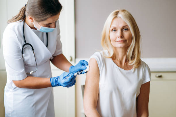 Vaccine covid-19. Female doctor or nurse giving shot or vaccine to a patient's shoulder. Vaccination and prevention against flu or virus pandemic stock photo