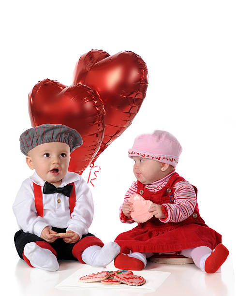 A baby girl and boy, dressed for a big date, snacking on heart-shaped...
