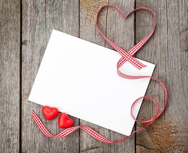 Valentine's day blank gift card and red candy hearts on wooden...