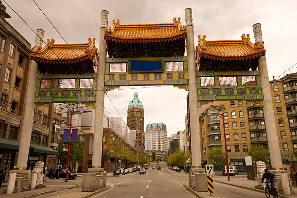 Vancouver Chinatown and Millenium Gate Pender Street leading through the Millennium Gate in Vancouver Chinatown with the Sun Tower in the background.  chinatown stock pictures, royalty-free photos & images