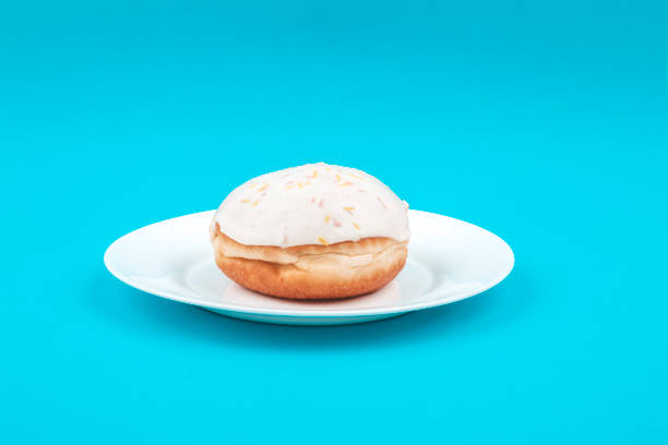 Vanilla donut on a white plate on a blue background  lepro stock pictures, royalty-free photos & images