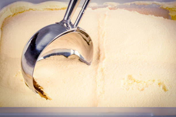 Vanilla ice cream being scooped out of tub stock photo
