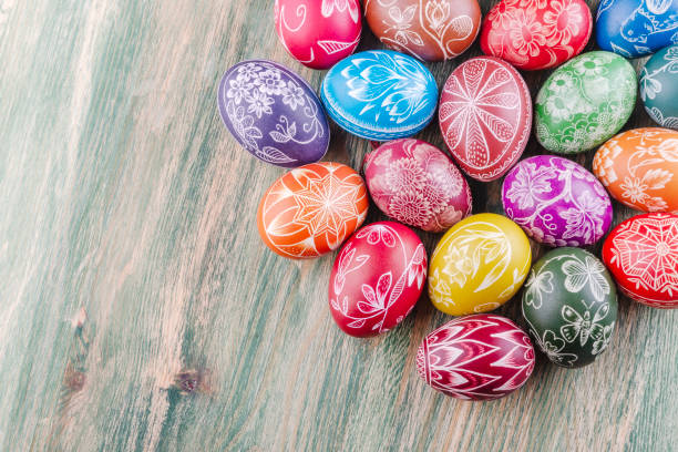 Variety of colorful handmade scratched easter eggs on wooden table stock photo