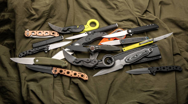 A variety of folding and pocket knives lie on khaki fabric. A versatile pocket tool and self-defense tool. stock photo