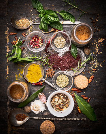 variety of oriental herbs and spices: Acetic tree, curry powder, paprika, cayan pepper, sira,Bay leaf on spoons and bowls, top view.  national cuisine  and cooking concept.