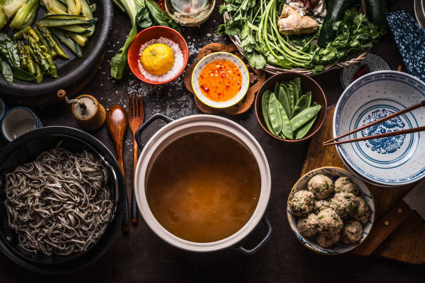 Various asian food ingredients for tasty soba noodles soup around cooking pot with delicious miso broth or stock on rustic kitchen table background, top view stock photo