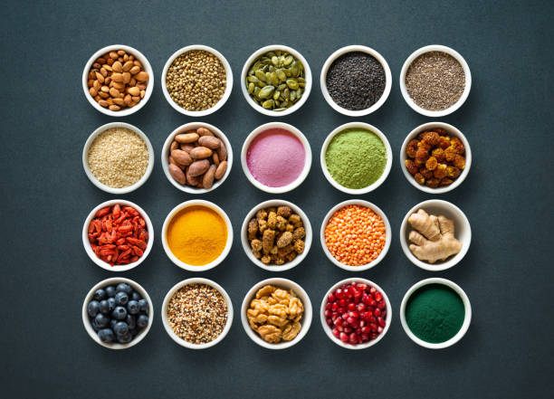diverse kleurrijke superfoods in kommen op donkere achtergrond - antioxidant stockfoto's en -beelden