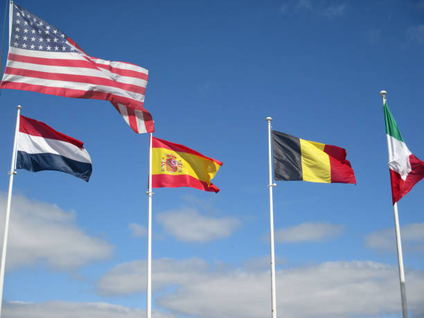 Various flags blowing in the wind American Netherlands Spanish French Italian stock photo