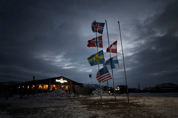 various flags of the Nordic countries are flying on the flagpole in wind against the background of the night sky in the clouds. Dramatic landscape stock photo
