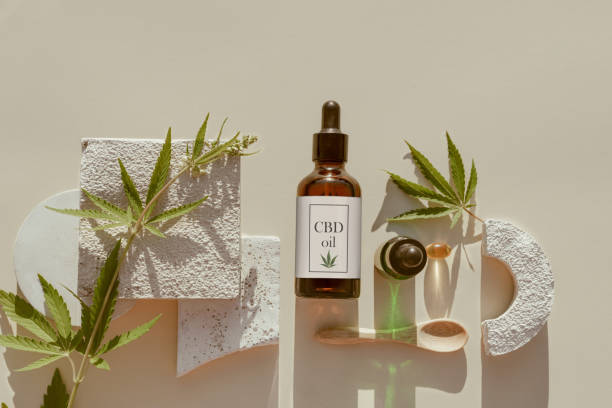 Various glass bottles with CBD oil, THC tincture and hemp leaves, capsule on beige background. Flat lay, minimalism. CBD oil cosmetics stock photo