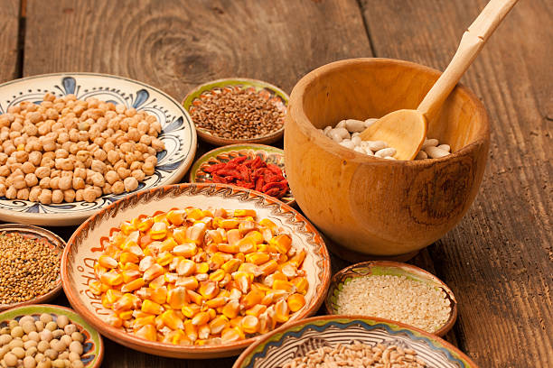 Various grain beans in small clay plates on wood background stock photo
