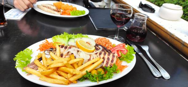 Various meat specialties, french fries and salad, with red wine stock photo