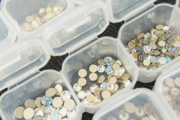 Various nail art rhinestones and accessories neatly organized in clear containers. stock photo