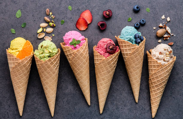 各種霜淇淋風味在錐藍莓，草莓，阿月渾子，杏仁、 橙、 櫻桃安裝暗石背景上。夏天和甜功能表的概念。 - ice cream 個照片及圖片檔