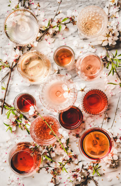 Various shades of rose wine over white marble background Various shades of rose wine. Flat-lay of rose wine of different colors in glasses and spring blossom flowers over white background, top view. Wine shop, bar, wine tasting, seasonal wine list concept rose wine stock pictures, royalty-free photos & images