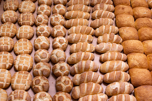 Various Types of Bread Buns displayed Orderly on Top of a Wooden Display Stand from an Italian Bakery.