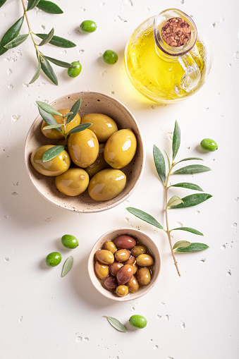 Various types of olives in bowl with an olive branch. Products made of olives.