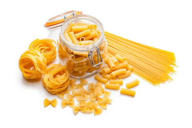 Various types of raw pasta isolated on white background Various types of raw pasta shot from above on white background. Types of pasta included in the composition are spaghetti, rigatoni, bow tie pasta and fettuccine. Predominant colors are yellow and white. High key DSRL studio photo taken with Canon EOS 5D Mk II and Canon EF 100mm f/2.8L Macro IS USM. uncooked pasta stock pictures, royalty-free photos & images