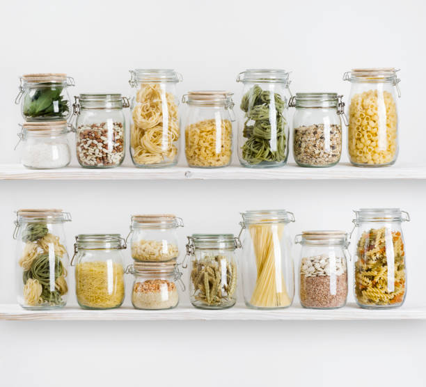 Various uncooked groceries in glass jars arranged on wooden shelves Various uncooked groceries in glass jars arranged on wooden shelves jar stock pictures, royalty-free photos & images