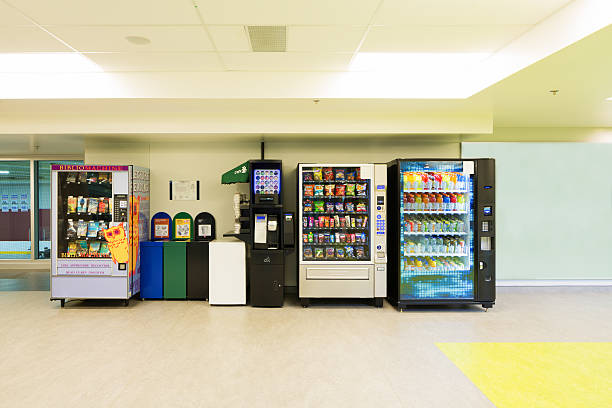 Various vending machines and trash cans lined up against a wall.