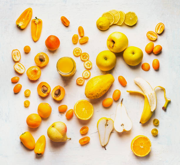 Various yellow and orange color fruits and vegetables on white table background. Flat lay stock photo
