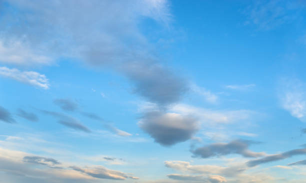 Vast blue sky background with scattered grey and white clouds stock photo