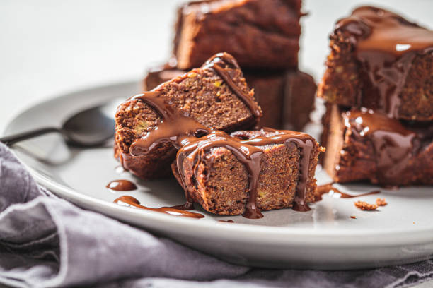 vegan brownie vierkantjes met donkere chocolade op grijs bord, close-up. veganistisch dessertconcept. - brownie stockfoto's en -beelden