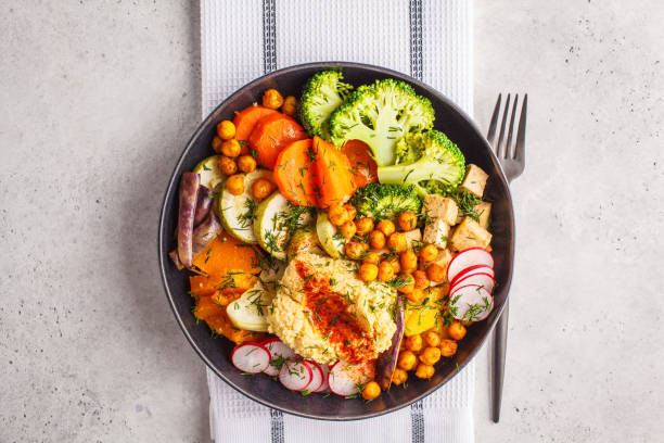 Vegan Buddha bowl with baked vegetables, chickpeas, hummus and tofu, top view. stock photo