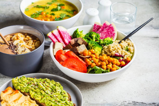 vegan lunch. chocolade smoothie bowl, buddha bowl met tofu, kikkererwten en quinoa, linzensoep en toast op een grijze achtergrond. - veganist stockfoto's en -beelden
