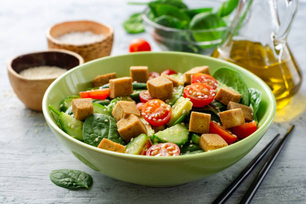 Vegan salad with spinach, cucumber, tomatoes, avocado, fried tofu and sesame stock photo