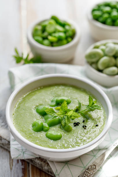 Vegetable cream soup. Broad bean soup sprinkled with  fresh mint and nigella seeds. Delicious and nutritious vegan food. Vegetable cream soup. Broad bean soup sprinkled with  fresh mint and nigella seeds. Delicious and nutritious vegan food. Healthy eating concept. broad bean stock pictures, royalty-free photos & images