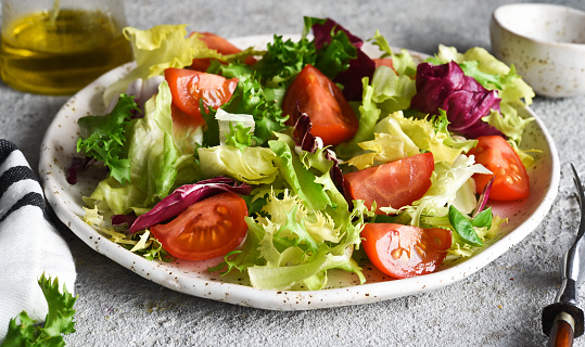 Vegetable mix salad with tomatoes and sauce on a concrete background.
