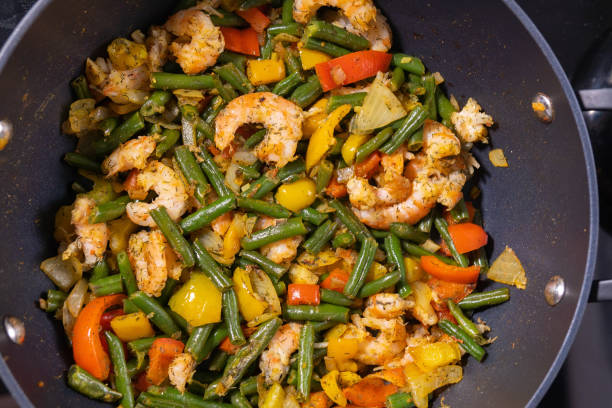 Vegetable stir fry with shrimps close-up in a frying pan. Cooking at home stock photo