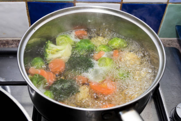 vegetables boiling in a saucepan on a hob vegetables boiling in a saucepan on a hob boiled stock pictures, royalty-free photos & images