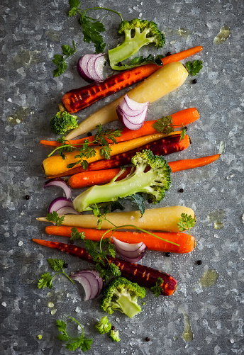 raw rainbow carrot , broccoli and onion for roasting, on the vintage metal background