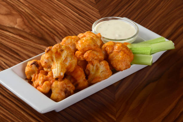 Vegetarian Buffalo Cauliflower Bites A vegetarian take on the classic Buffalo chicken wings - spicy baked cauliflower bites served with celery sticks and blue cheese dipping sauce. buffalo new york stock pictures, royalty-free photos & images