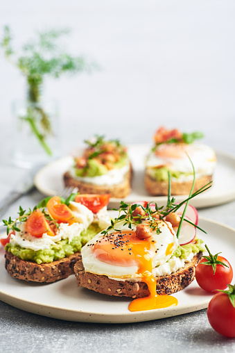 Healthy vegetarian sandwiches with egg tomatoes avocado cream and cheese garnished with chia seeds and aromatic herbs. Vegetarian sandwich.