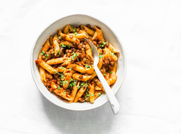 Vegetarian lentil Bolognese sauce with penne pasta on a light background, top view. Healthy eating diet concept food Vegetarian lentil Bolognese sauce with penne pasta on a light background, top view. Healthy eating diet concept food bolognese sauce stock pictures, royalty-free photos & images