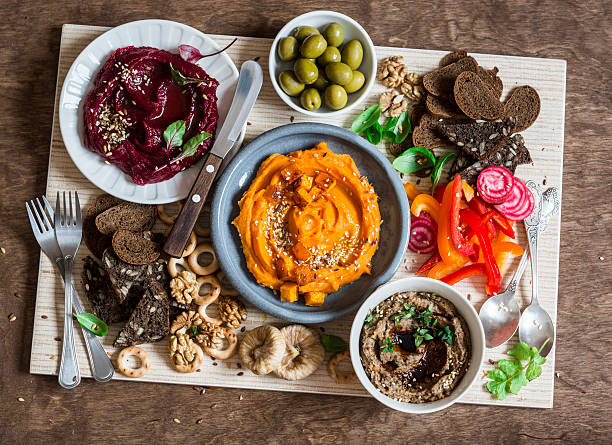 Vegetarian snack table. Pumpkin, beets hummus, mushroom pate, vegetables, bread Vegetarian snack table. Pumpkin, beets hummus, beans and mushroom pate, vegetables, nuts, bread on a wooden table, top view. Flat lay pate stock pictures, royalty-free photos & images