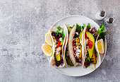 Vegetarian snack tacos with grilled vegetables, avocado, feta cheese, salad with small sweet peppers and sauce with lemon and olive oil. food background