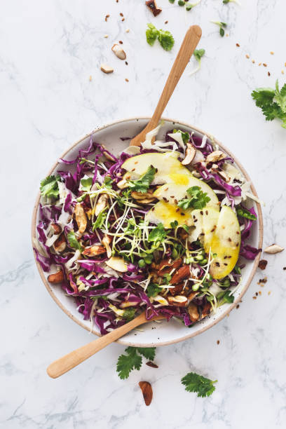 Vegetarian Summer Salad with Red Cabbage, White Cabbage, Apple, Almonds, Sprouted Seeds and Turmeric Sauce or Turmeric sauce stock photo