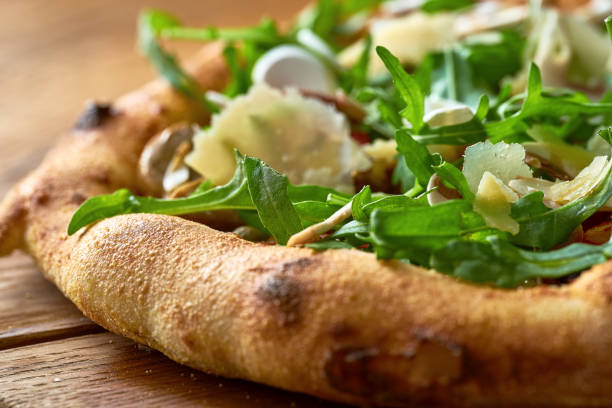 Vegetarian wood-fired pizza with arugula, vegetables and parmesan on wood board. Selective focus stock photo