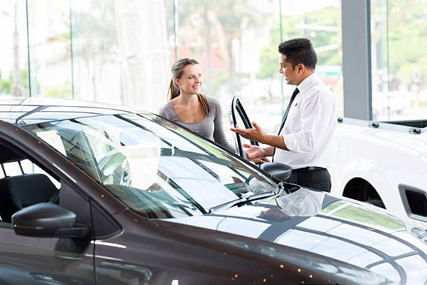 vehicle dealer showing young woman new car friendly vehicle dealer showing young woman new car car salesperson stock pictures, royalty-free photos & images